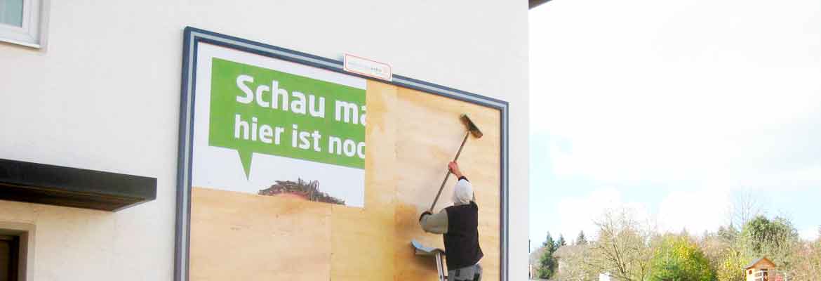 Mitarbeiter plakatiert eine Großfläche