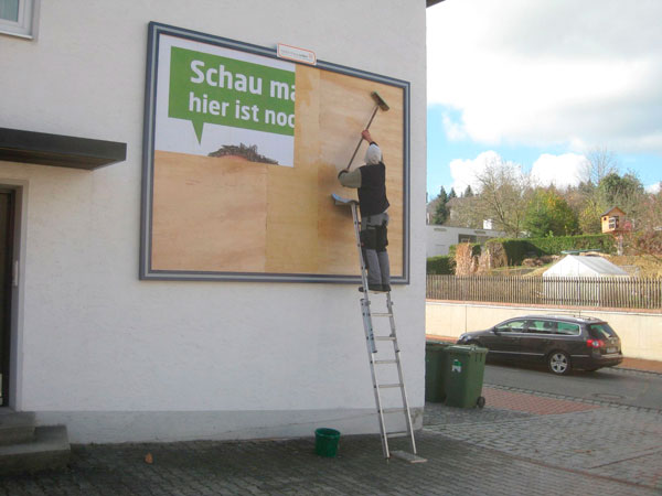 Mitarbeiter plakatiert eine Großfläche